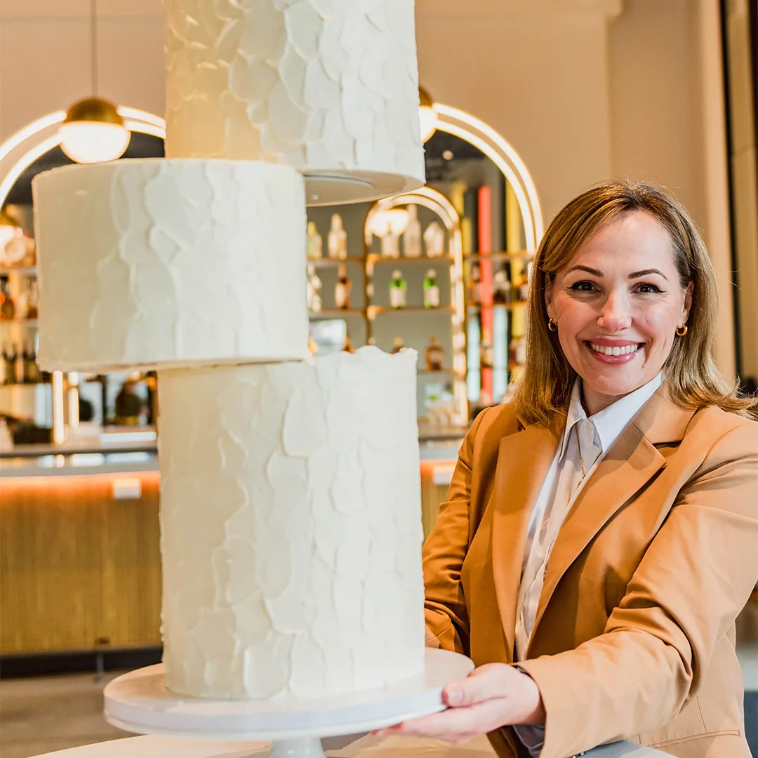 Andreza, confeiteira da Bloom Cakes, ao lado de um bolo autoral